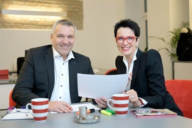 Zwei Personen mit Unterlagen und Kaffeetassen im Beratungsgespräch